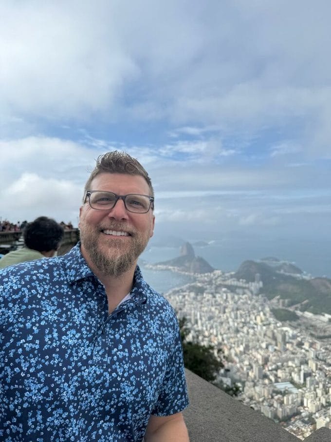 Dr. Jason Gladwell at the Corcovado overlook in Rio de Janeiro with Sugarloaf Mountain and Copacabana behind him