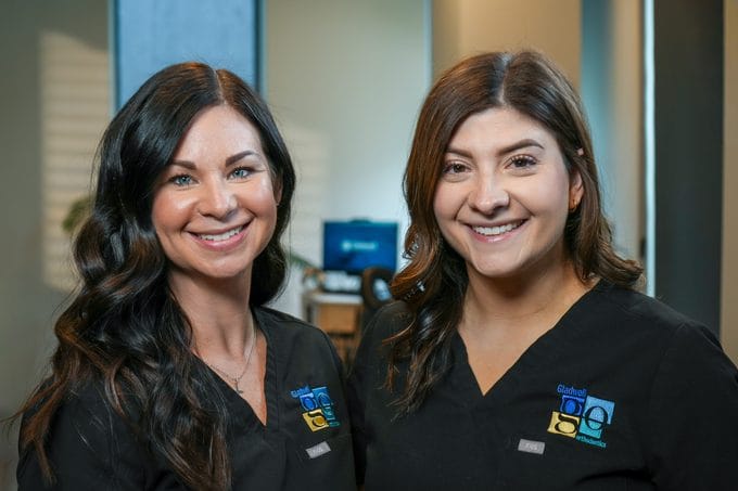 Gladwell Orthodontics front desk team members in branded scrubs ready to greet patients